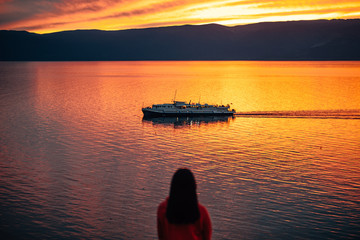 Girl looks at the sunset on the lake cruise boat