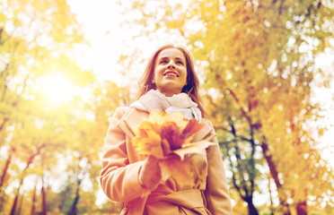 beautiful woman with maple leaves in autumn park