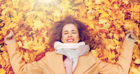 beautiful happy woman lying on autumn leaves