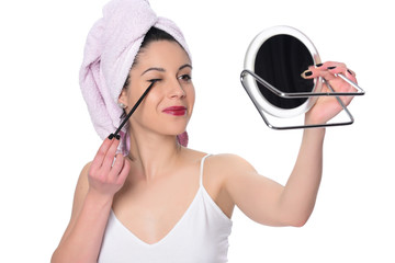  A young woman applying makeup on her face with a brush