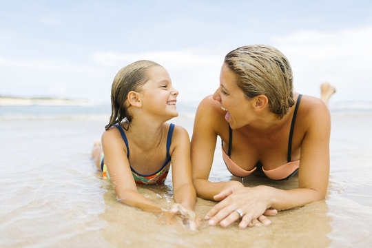 Fototapeta Mother lying with her daughter on the beach