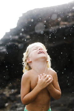 Shirtless boy playing with rain