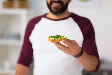 man eating avocado sandwich at home kitchen