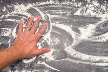 Eine Hand verwischt Mehl auf einer Küchen Arbeitsplatte