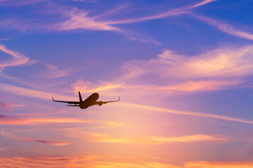 Fototapeta na wymiar Silhouette passenger airplane flying away in to sky high altitude above the sun during sunset