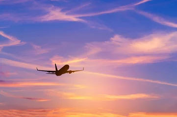 Foto op Plexiglas Silhouetpassagiersvliegtuig dat tijdens zonsondergang wegvliegt naar de hemel op grote hoogte boven de zon © Soonthorn