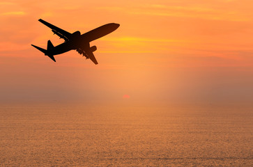 Fototapeta na wymiar Silhouette passenger airplane flying away in to sky high altitude during sunset