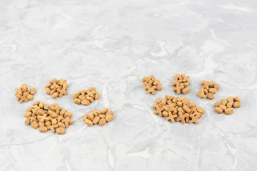 Two footprint laid out of dry brown cat food on old gray concrete floor