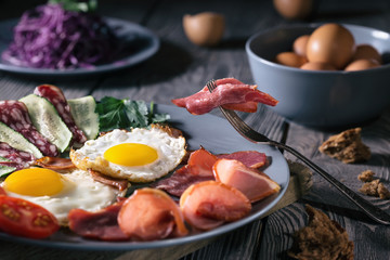 Fried eggs with bacon and vegetables on a blue plate