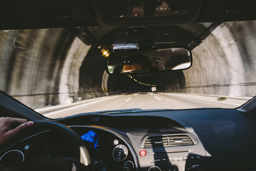 Cockpit view driving car inside a dark tunnel