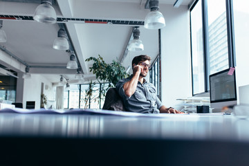 Young businessman talking on cellphone in modern office
