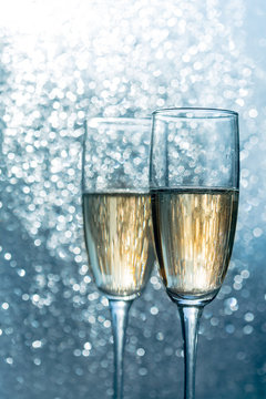 Two champagne glasses of toasting against dark gold bokeh background