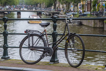 Fototapeta na wymiar A bike attached to a bridge in Amsterdams Canal district - AMSTERDAM - THE NETHERLANDS - JULY 20, 2017