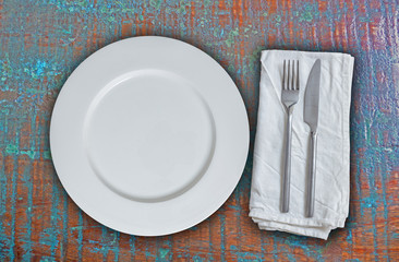Leerer Teller mit Besteck auf türkisem vintage Holz