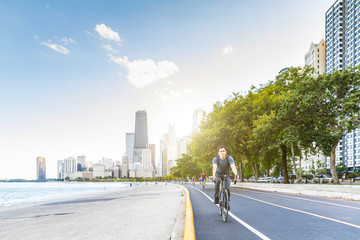 Naklejka premium Man cycling in Chicago with city on background