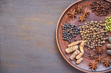 Aromatic spices on a dark plate - star anise, fragrant pepper, calamus root, cinnamon, nutmeg on dark brown background close up with copy space on the left side. Spices texture background. Top view