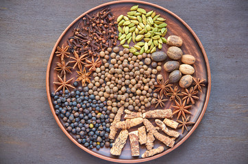 Aromatic spices on a dark plate -star anise, fragrant pepper, calamus root, cinnamon, nutmeg on dark brown background. Spices texture background. Top view