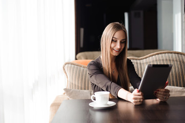 Beautiful pregnant woman using digital tablet at table in cafe