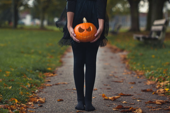 Girl in a black tutu and tights holding a carved pupkin - Powered by Adobe