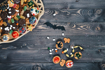 Bat, cookies, marmalade, marshmelow, snakes. muffins on an old wooden countertop