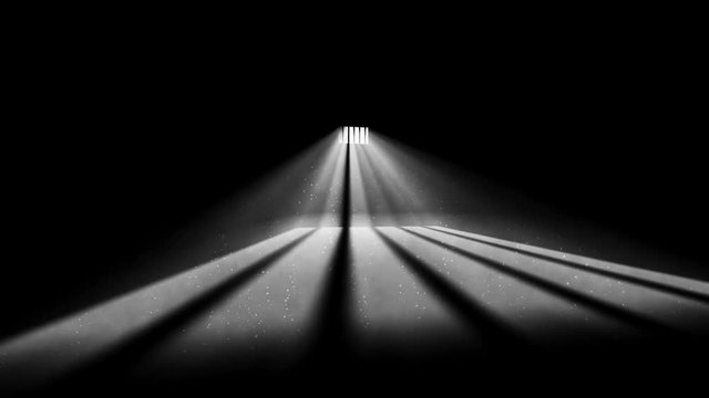 Interior of a prison cell with foggy light shining through a barred window and shadows on a floor. 
