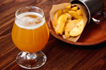 Potato chips and glass of beer on a wooden table.