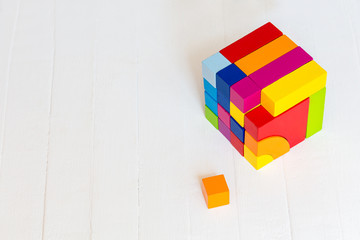 Colored wooden blocks, cubes, build on a light wooden background.A cube of colored wooden details