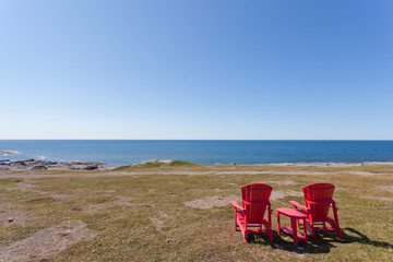Fototapeta na wymiar Barren coastal landscape with red wooden chairs