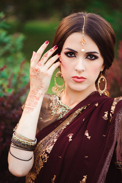 Portrait of beautiful indian girl. Young hindu woman model with tatoo mehndi and kundan jewelry. Traditional Indian costume saree.
