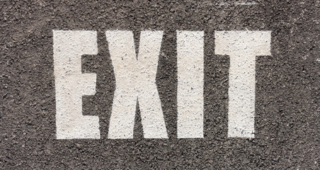 close up of white traffic exit sign on asphalt in a parking area in the city for traffic rule
