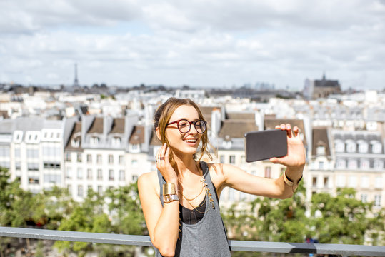 Young woman making selfie photo on the Paris skyline background