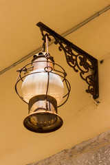 close up of old glass metal oil mediterranean lantern on old house in small romantic village in the sun