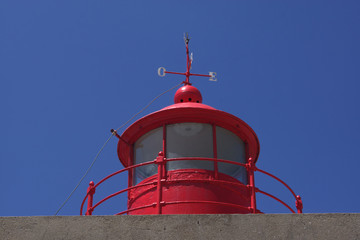 phare rouge sur ciel bleu avec girouette