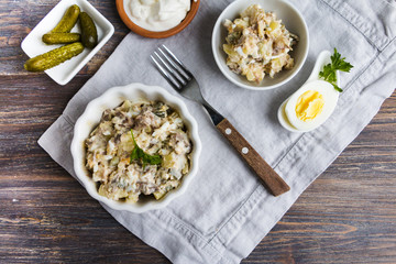 Potato and meat salad - top view on rustic wooden table.