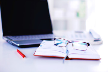 Office table with blank notepad and laptop