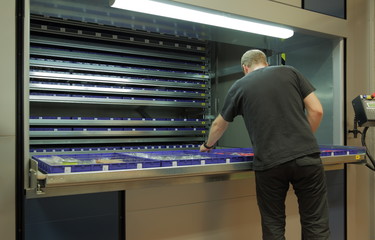 Male worker at automated vertical carousel storage unit in the warehouse