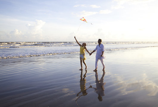 Teenage girl flying kite in seabeach and walking with grandfather