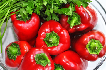 Raw red organic peppers with  bunch of aromatic green spice parsley in a glass bowl ready to cook with isolated on white