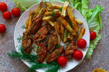 Chicken ribs in honey sauce with French fries and vegetables.