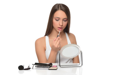  A young woman applying makeup on her face with a brush
