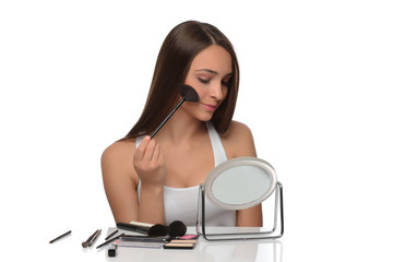  A young woman applying makeup on her face with a brush