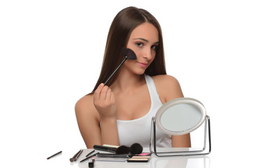  A young woman applying makeup on her face with a brush