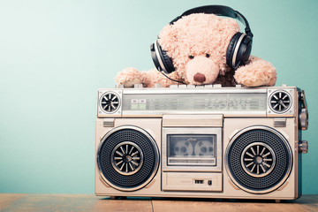 Retro radio recorder and toy Teddy Bear with headphones in front mint background. Vintage style...