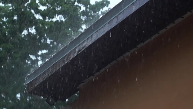 Heavy rain pouring off roof. A mildly heavy rain storm in Naples Florida is pounding on the roof top and pouring off the edge during summer rainy season creating flash flood conditions , with audio.