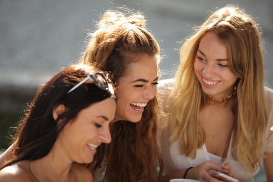 Cheerful brunette, blonde and dark-haired girls laughing in sunl