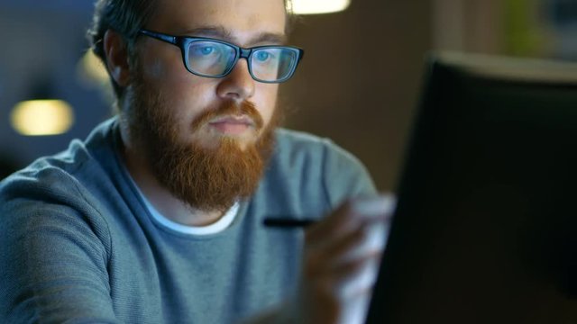 Talented Young Concept Artist Drawing on a Digital Pen Display Tablet While Sitting at His Working Place in Modern Loft Office. Late at Night. Shot on RED EPIC-W 8K Helium Cinema Camera.