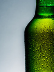 A cold green beer bottle with water drops