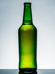 A cold green beer bottle with water drops
