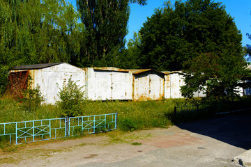 Obraz premium Old abandoned garages near houses. Dead radioactive zone. Consequences of the Chernobyl nuclear disaster, August 2017