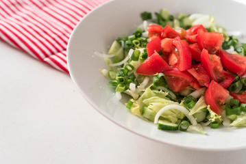 Georgian salad tomatoes cucumbers, onions, on white table red napkin striped